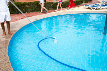 Man cleaning a swimming pool in summer. Cleaner of the swimming pool