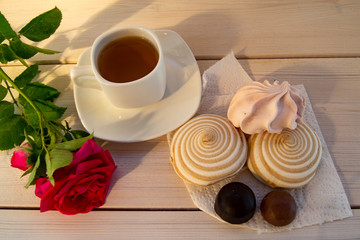 Delicate multicolored marshmallows on white openwork plate. Still life with marshmallows, a Cup of tea and a rose on vintage background.