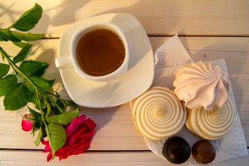 Delicate multicolored marshmallows on white openwork plate. Still life with marshmallows, a Cup of tea and a rose on vintage background.