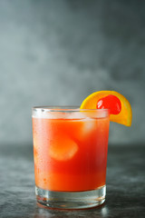 Summer cocktail. Orange juice with mint, syrop, fruit slices and cherry with ice. Dark background.