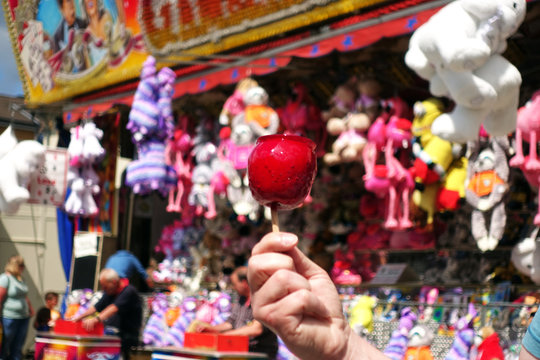 sweet candy apple on county fair or festival. red candy apple covered in red caramel, at holiday vacation event or amusement park