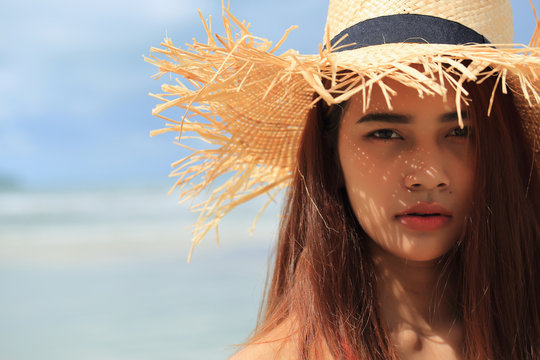 The image of an Asian woman with honey-colored skin standing on the beach.