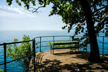 bench under a tree in the shadow, with view on the Adriatic sea and island Cres.. Boulevard between Opatija and Lovran. Croatia
