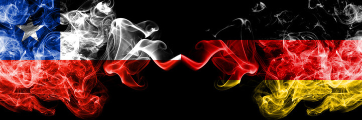 Chile vs Germany, German smoky mystic flags placed side by side. Thick colored silky smokes combination of Germany, German and Chilean flag