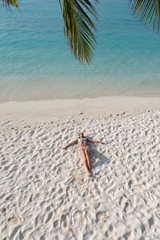 Fototapeta na wymiar Paradise on earth - the girl lies on a white beach on a paradise island.
