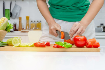 Obraz na płótnie Canvas Diet. young pretty woman in green shirt cutting cooking and knife preparing fresh vegetables salad for good healthy in kitchen at home, healthy lifestyle, cooking, healthy food and dieting concept