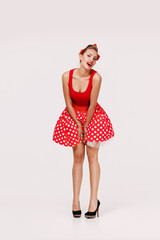 smiling pin up woman in polka dot red dress isolated on gray background. cute girl posing in retro style