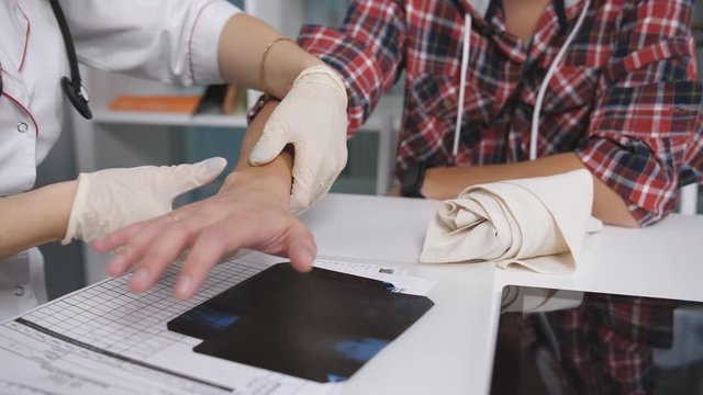 The doctor examines an x-ray of the damaged wrist of the patient. The doctor examines the patient's arm. Doctor inspects injury
