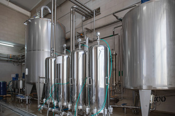 Large reservoirs and tanks and pipes with manometers in modern juice and water production plant....