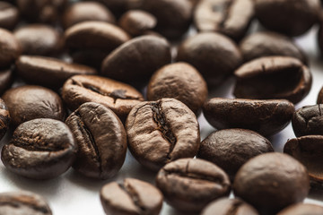 Coffee beans on white background, macro photo. Brown aromatic roasted seeds