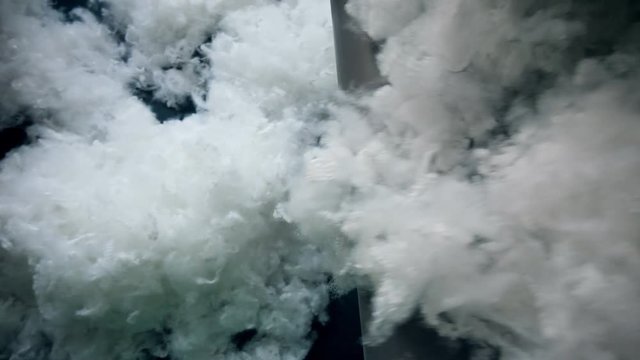 Polyester batting falling from a factory conveyor.