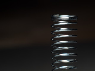 Close-up of a coil spring on a gray background.