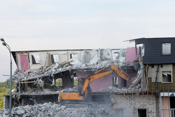 An excavator demolishes a multi-storey building with a ladle. Technique destroys the building, is fittings, concrete and stones. Destroyed house, concrete, fittings. Similiar