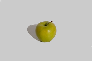 Apple shot in close-up with a shadow on a white background. Green apple isolated.