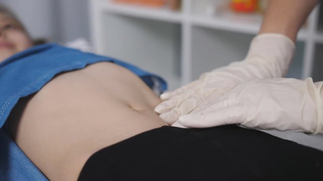 The doctor palpated the abdomen of a young patient in a medical office., close-up.