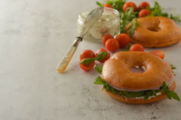 Healthy turkey ham sandwich on a bagel with greens and tomato. Breakfast. Copy space.