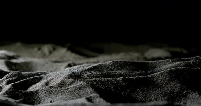 Hands close-up that touch and sprinkle sand on the sandy beach late at night.