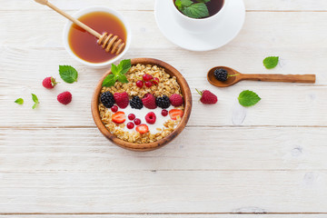 granola with berries on white wooden background