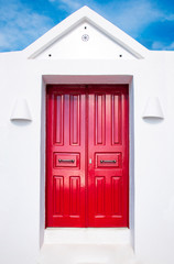 Beautiful old red door on white facade of greek architecture against the blue sky, Santorini island, Greece, Europe. Beautiful details of the island of Santorini. Famous travel destination
