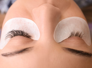 Young woman undergoing eyelash extensions procedure, closeup