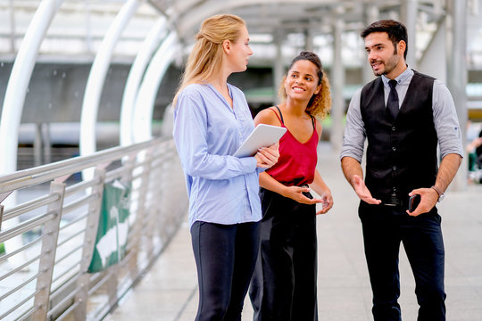 One business man discuss about work with his team, two women with one mixed race tan skin and white Caucasian woman who holds tablet.