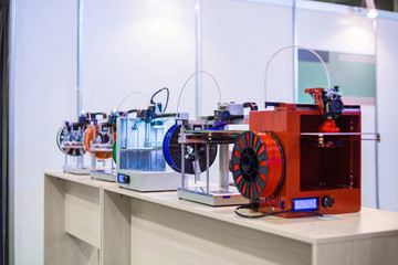 Automatic 3D printers in row during work at modern technology exhibition. 3D printing, additive...