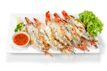 Grilled 5 black tiger shrimps with boiled potatoes, slice of lime, tomato fresh vegetables and chili seafood sauce on white square plate isolated on white background with shadow high angle Top view