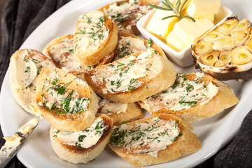 Sliced traditional toast bread with butter, garlic and herbs on a white plate