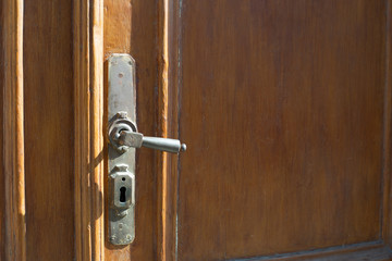 Iron brass door knob on solid wood door – Classic and vintage forged metallic handle with subtle decorations