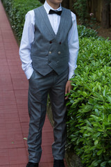 the child model wearing suit and bow tie at the garden.