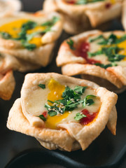 Ideas and recipes for healthy Vegan Shakshouka cups with vegan tofu eggs and turmeric yolk. Puff filo pastry,tomato and vegetable sauce and fresh green parsley. Copy space for text. Vertical.