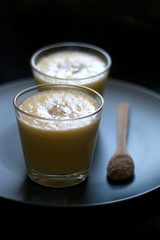 Two glasses of refreshing mango lassi drink, decorated with cardamom. Dark background, selective focus.