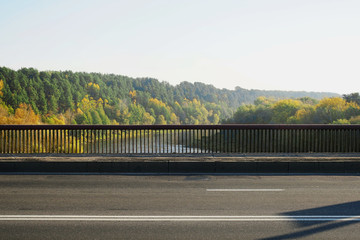 side view of railing of large wide bridge over river, empty asphalt highway foreground