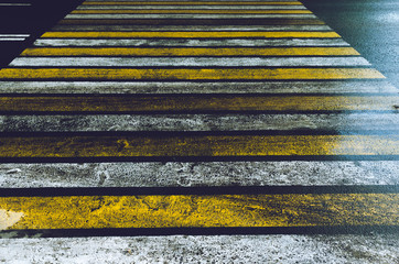 Slippery road with a pedestrian crossing painted in yellow and white Zebra with glare after rain.