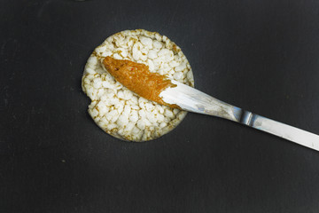 crunchy natural peanut butter sandwich  on rice cake bread on black slate background with knife peanut butter with knife with free copy space. Proper nutrition diet vegetarian breakfast