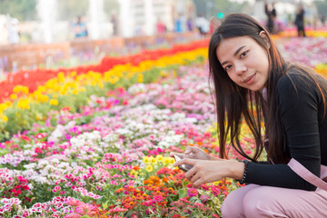 Beautiful asian girl taking photo on flowers by telephone at Bangkok , Thailand. Beautiful Women with flowers and nature concept.