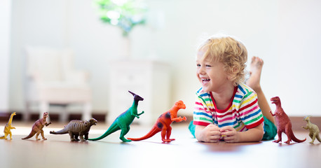 Child playing with toy dinosaurs. Kids toys.