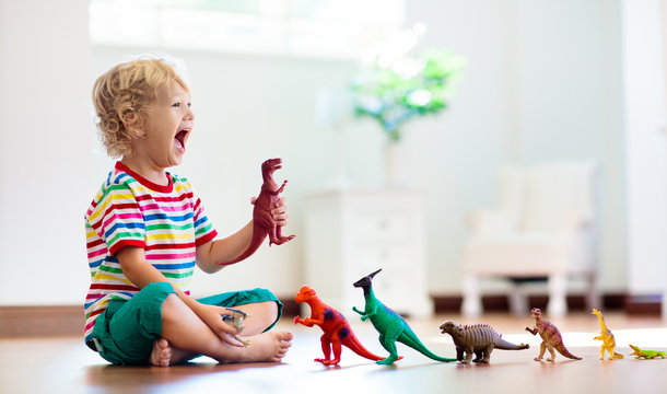 Child playing with toy dinosaurs. Kids toys.