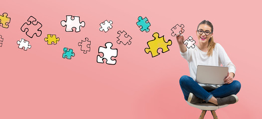 Puzzle pieces with young woman using her laptop