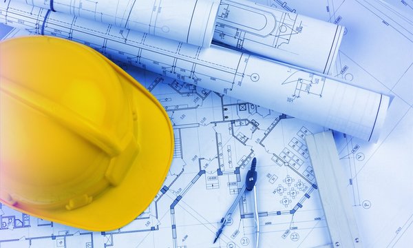 Blueprints construction and a yellow hardhat with a compass