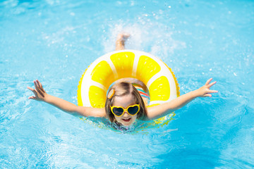 Child in swimming pool on ring toy. Kids swim.
