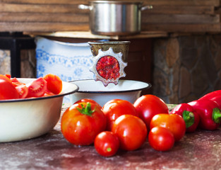 ripe tomatoes, red sweet peppers and a handmade vintage meat grinder on the table in the village kitchen