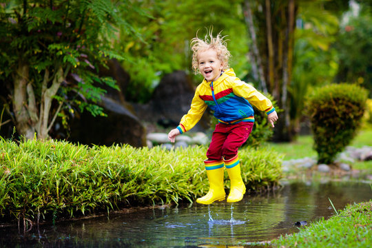 Child playing in puddle. Kids jump in autumn rain
