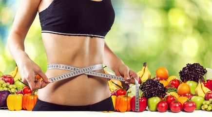 Young woman with measuring tape on healthy food background