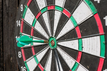 Darts board on the wall with wooden boards. Darts driven into the center