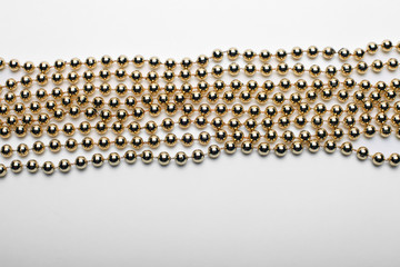 Gold round beads garland on white backgroun. Flat lay.  Top view.