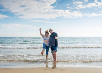 Senior couple in love walking on the beach having fun in a sunny day
