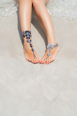 Chick vacation vibe concept. Woman legs with leg jewellery on the tropical white sand beach. Nisi beach in Aya Napa resort summer vibe.