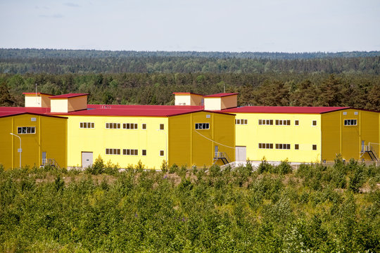 Big Yellow Industrial Building On Wide Panoramic View Of Summer Green Forest Background On The Horizon