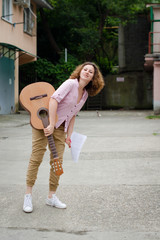 Beautiful girl playing acoustic guitar on street. Funny young woman presenting her song outdoors.